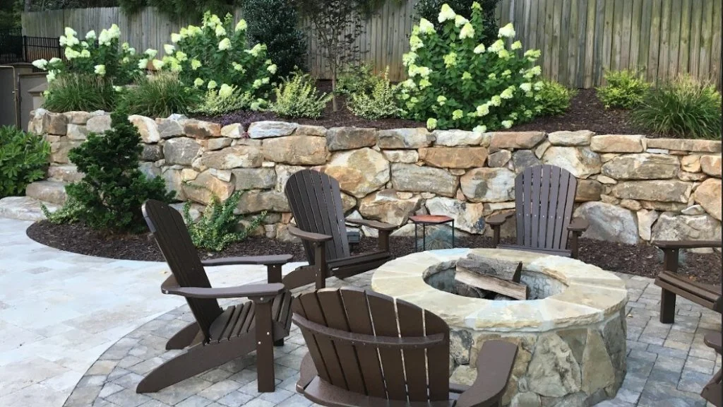 Outdoor living space with a fire pit and boulder retaining wall in Cornelius, NC.