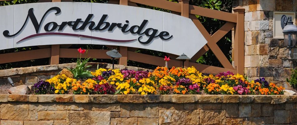 Colorful flowers in a planter bed with a community sign in Charlotte, NC.