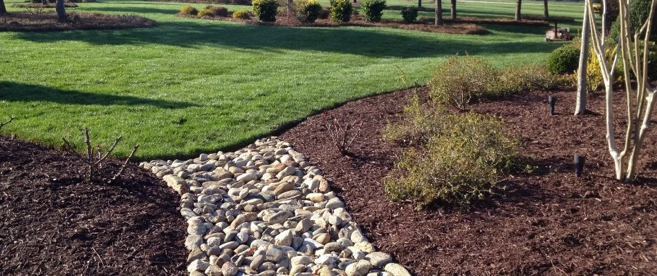 Landscape with mulch and a creek bed and a lawn in Newell, NC.