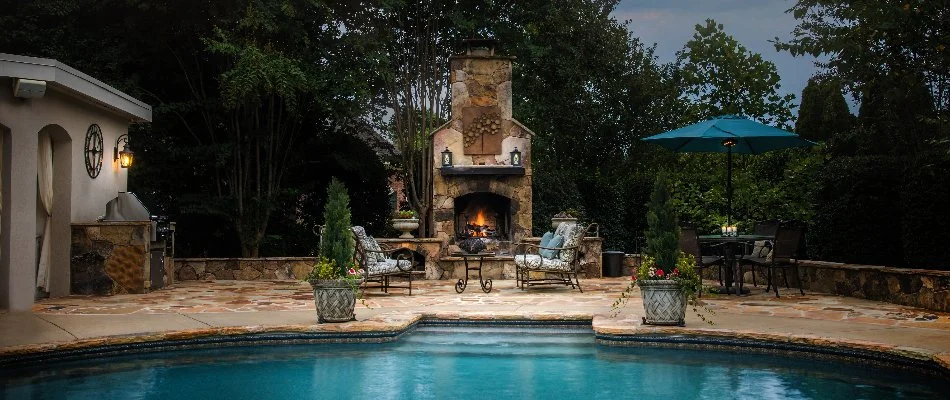 Outdoor fireplace on a flagstone patio in Enochville, NC, with a pool.