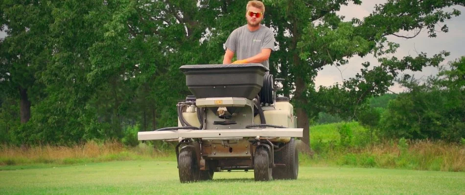 Technician using lawn care equipment to treat grass, ensuring a healthy and well-maintained lawn in Charlotte, NC.