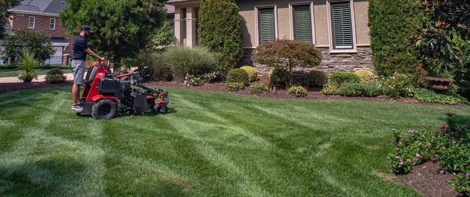 Worker aerating a lawn.