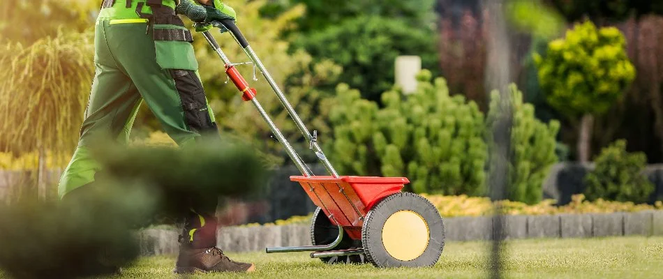 Worker in Charlotte, NC, fertilizing a lawn.