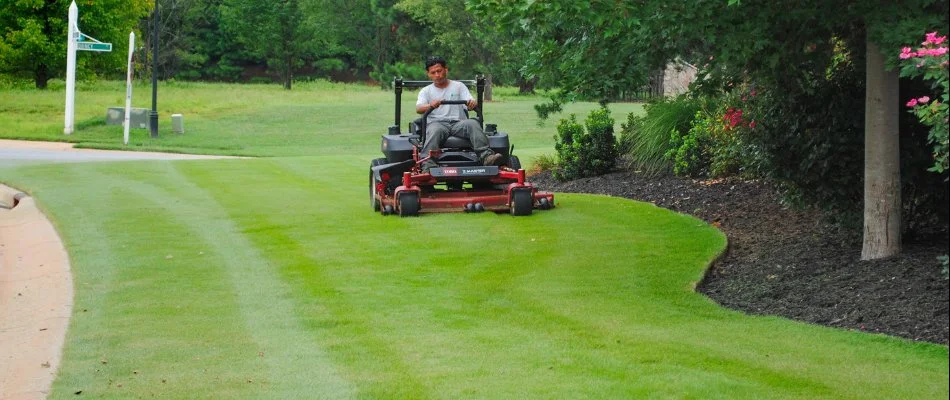 Worker in Charlotte, NC, mowing a lawn.