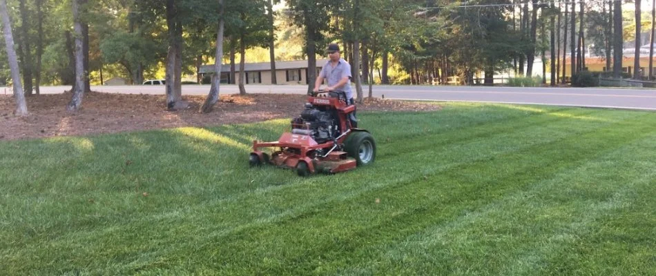 Worker in Charlotte, NC, mowing a lawn.