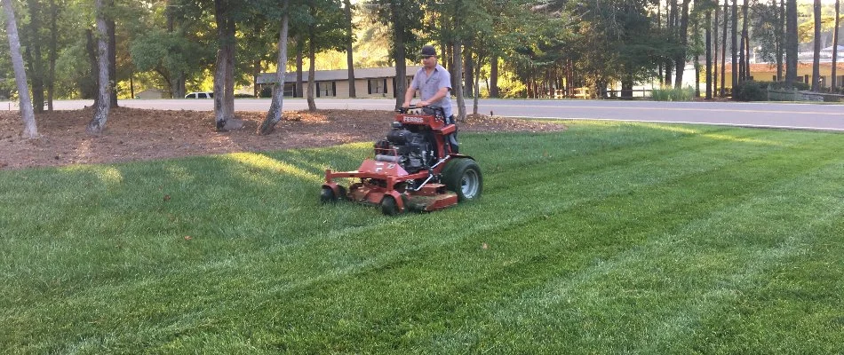 Worker in Lake Norman, NC, mowing a lawn.
