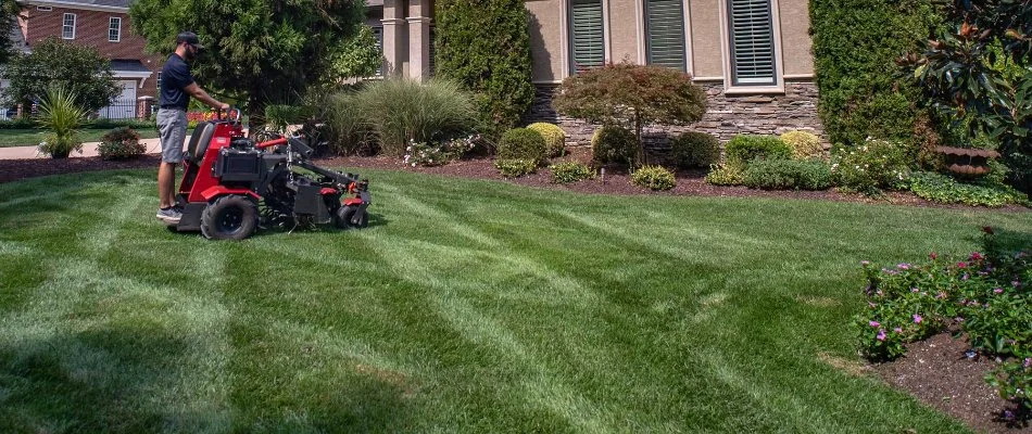 Worker riding on an aerator across a lawn in Enochville, NC.