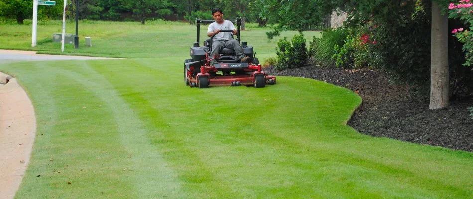 Worker riding on a mower cutting grass in Baxter Village, SC.
